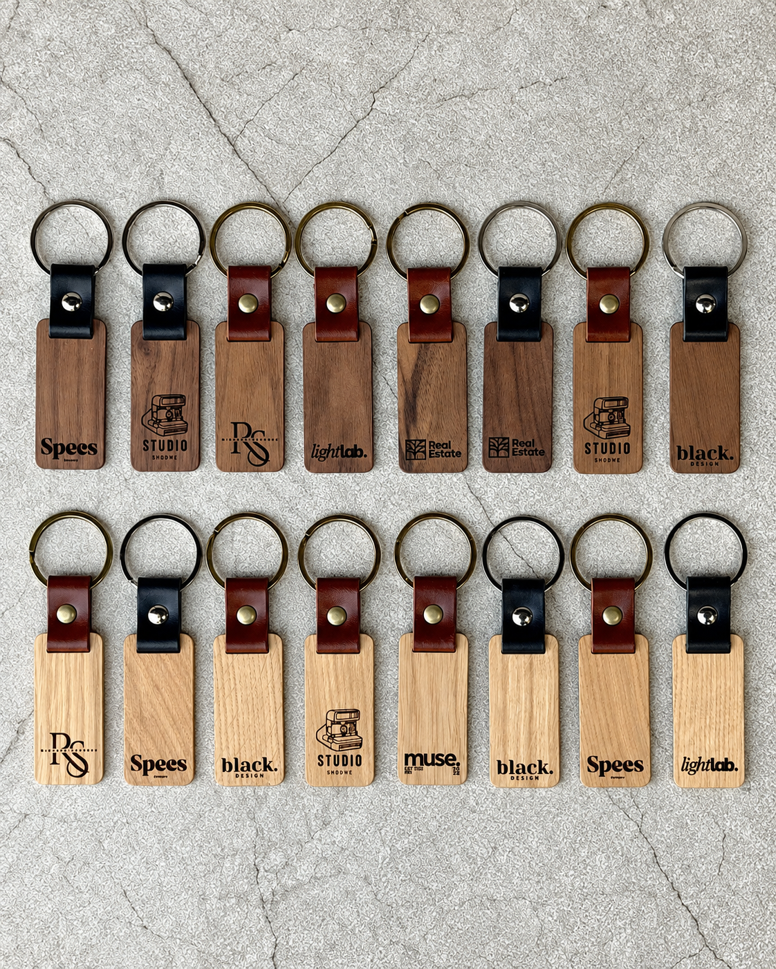 Personalised wooden keychains in oak and American walnut with genuine leather, shown with multiple laser engraved designs