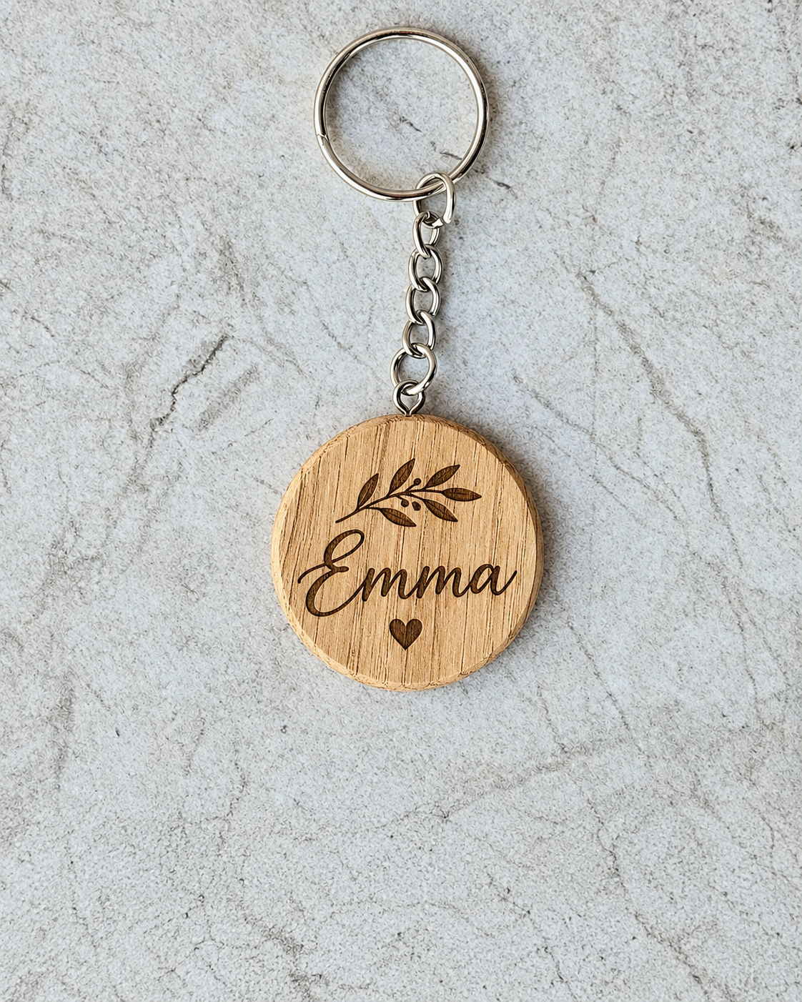 Personalised rounded oak keychain engraved with the name Emma, botanical detail and heart
