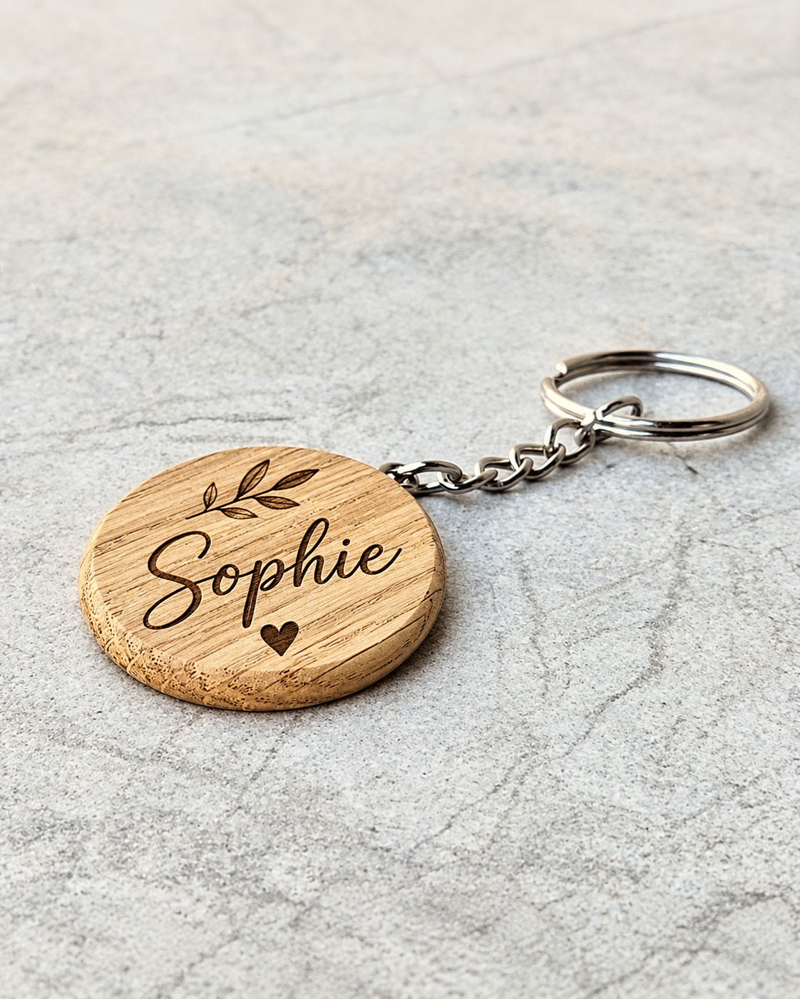 Personalised rounded oak keychain engraved with the name Sophie, botanical detail and heart